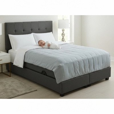 Co-sleeper bassinet attached to a parent's bed, with a sleeping baby inside